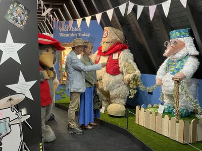 Marcus pointing at the Womble sculptures while Marianne laughs and Orinoco is watching